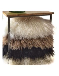 a wooden table topped with a black, white and brown shaggy rug next to a green plate