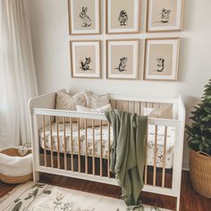 a white crib with pictures on the wall above it and a rug in front of it