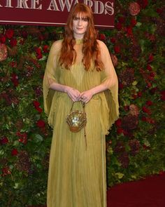 a woman with red hair wearing a yellow dress and holding a golden ball in her hands