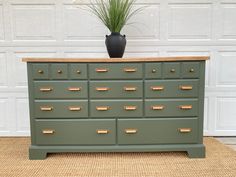 a green dresser with gold handles and brass knobs in front of a white garage door