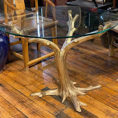 a glass table with wooden legs on a wood floor in front of a blue vase