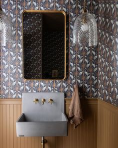 a bathroom sink sitting under a mirror next to a wall mounted faucet in front of a wooden paneled wall