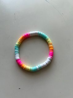 a bracelet made out of multicolored beads on a table with a white background