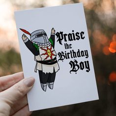 a hand holding up a card that says praise the birthday boy with a knight on it