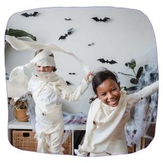 two children dressed up as bats in front of a wall with fake bats on it