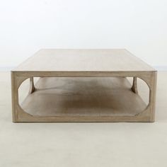 a wooden coffee table sitting on top of a white carpeted floor with no one around it