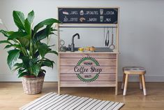 a potted plant sitting next to a coffee shop sign on top of a wooden table