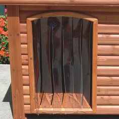 a wooden structure with an open window on the side and flowers in the back ground