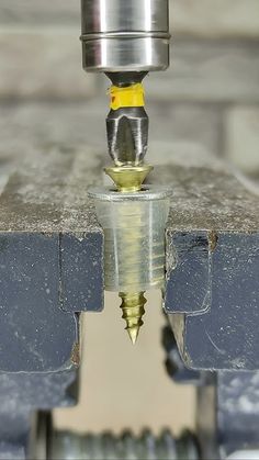 a machine that is cutting metal with a yellow tip on it's head and some sort of tool in the middle