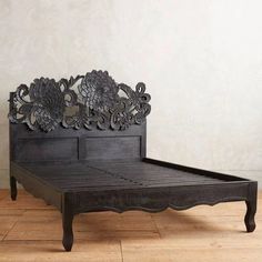 a black bed frame sitting on top of a hard wood floor next to a wall