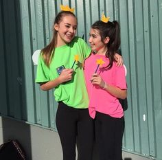 two girls in matching shirts are standing next to each other and one girl is holding a pinwheel