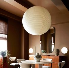 a dining room table with white chairs and a round light fixture hanging from the ceiling