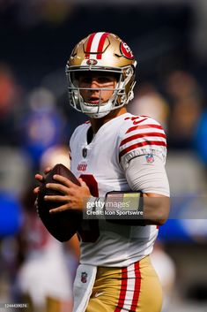 a football player holding a ball in his hands and wearing a helmet on the field