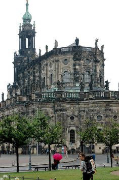 people are walking around in front of an old building with many spires and windows