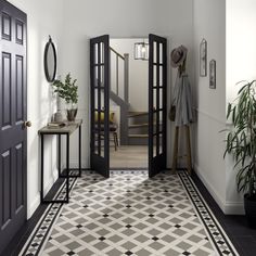 an entry way with black doors and tiled flooring, potted plants on either side