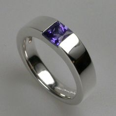 a white gold ring with an amethorate stone in the center, on a plain surface