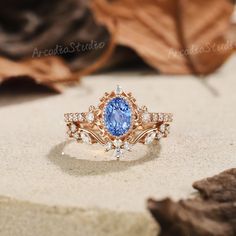 a blue and white diamond ring sitting on top of a table next to some leaves