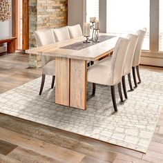 a dining room table with six chairs and a rug on the floor in front of it