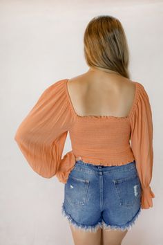 This orange crop top features a ruched smocked body and drawstring bust. It can be worn on or off the shoulder. The model is wearing a size medium. Off-shoulder Top With Smocked Bodice For Fall, Chic Smocked Bodice Crop Top, Chic Cropped Top With Smocked Bodice, Casual Tops With Elastic Waistband And Fitted Design, Summer Cropped Smocked Bodice Crop Top, Spring Orange Cropped Crop Top, Chic Fitted Crop Top With Elastic Waistband, Ruched Stretch Crop Top For Fall, Stretch Ruched Crop Top For Fall