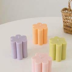 four candles sitting on top of a table next to a basket and wicker basket