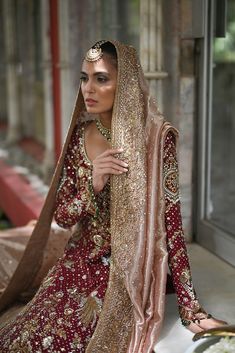 a woman in a red and gold bridal dress sitting on the ground with her hands behind her head