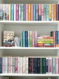 a book shelf filled with lots of colorful books on top of white shelves next to each other