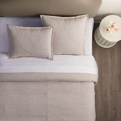 a bed with white and grey striped sheets