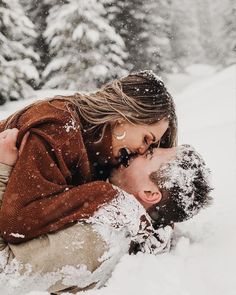 a man and woman are laying in the snow with their noses close to each other