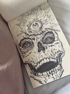 a drawing of a skull with an eye on it's forehead laying on a bed