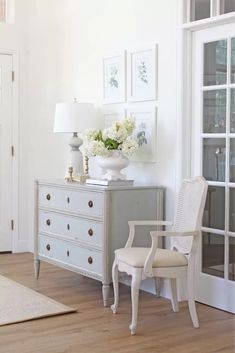 a white chair sitting next to a dresser on top of a hard wood floor