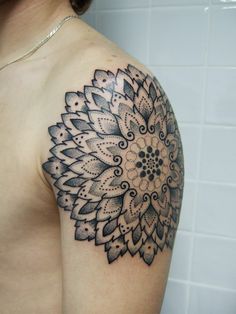 a woman's shoulder with a tattoo design on it and a flower in the middle