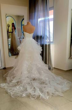 a white wedding dress on display in front of a window with sheer tulle skirt