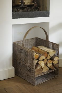 a basket with logs in front of a fireplace