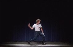 a man in white shirt and black pants on stage