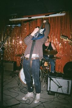 a man standing in front of a microphone and guitar