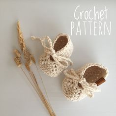 two crocheted baby shoes next to a dried plant