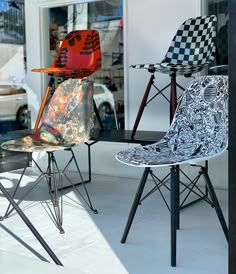 three chairs sitting on top of each other in front of a store window with cars parked behind them