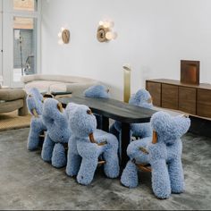 a group of teddy bears sitting at a table in a living room next to a couch