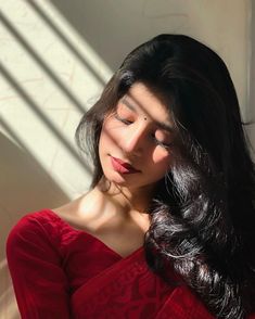 a woman with long black hair wearing a red dress and looking off to the side