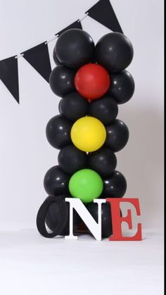 the balloon tower is decorated with black, red, yellow and green balloons that spell out n e