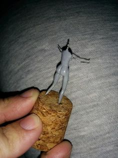 a person holding a tiny figurine on top of a cork