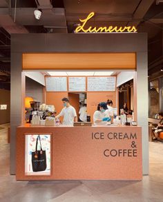 an ice cream and coffee shop with two people behind the counter in front of it