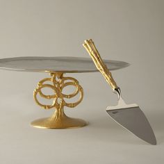 a cake stand with a gold tree on it and a metal spatula next to it