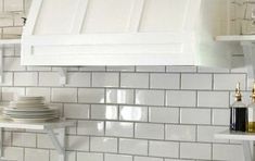 a kitchen with white tile and open shelving above the stove top is seen in this image