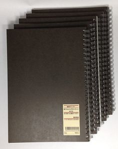 five black spiral notebooks lined up next to each other