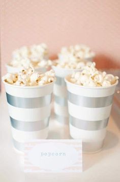 three cups filled with popcorn sitting on top of a table next to a sign that says popcorn