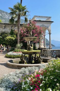 an outdoor fountain surrounded by flowers and palm trees