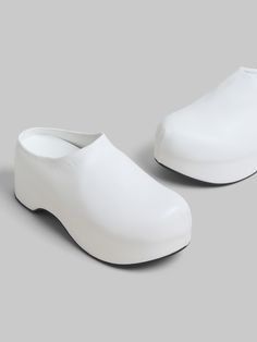 Chunky clog sabot with lightweight wooden platform sole, covered entirely in sleek nappa leather. Subtly embellished with debossed Marni lettering along the edge. Leather insole and ribbed rubber outsole. Modern Slip-on Clogs With Rubber Sole, Modern Slip-on Closed Toe Clogs, White Platform Clogs With Closed Toe, White Closed Toe Platform Clogs, White Leather Slip-on Platform Slippers, Modern Slip-on Clogs With Flat Heel, Synthetic Platform Clogs With Flat Heel, Leather Clogs With Chunky Platform, Leather Clogs With Chunky Platform And Round Toe