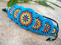 Stunning wide rosette embroidered with beads bracelet, inspired by the vibrant aesthetics of Native American and hippie styles! Handcrafted with intricate attention to detail, this multicolored accessory is a true statement piece that effortlessly blends traditional and bohemian influences. The colorful beads, meticulously sewn onto the rosette, create a mesmerizing mosaic of hues, while the wide design ensures a comfortable fit on your wrist. Perfect for those who appreciate unique jewelry, thi Multicolor Southwestern Cuff Bracelet For Festivals, Southwestern Multicolor Cuff Bracelet For Festival, Southwestern Style Multicolor Cuff Bracelet For Festival, Bohemian Cuff Bracelet With Colorful Beads For Festivals, Bohemian Adjustable Embroidered Bracelets, Bohemian Embroidered Adjustable Bracelets, Southwestern Festival Cuff Bracelet With Round Beads, Southwestern Style Multicolor Beaded Cuff Bracelet, Bohemian Embroidered Bracelets For Festivals