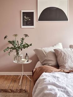 a bedroom with pink walls and white bedding, two framed pictures on the wall